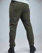khaki green pants with waaka logo on a grey background back view. core performance pant
