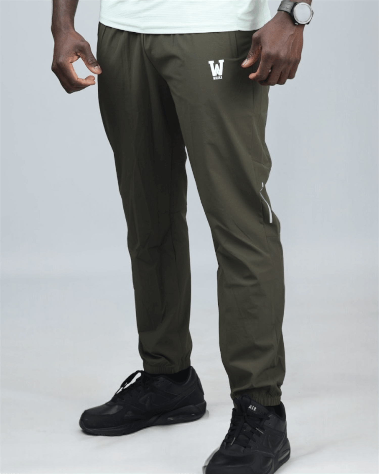 Person wearing green jogger pants with a logo on a gray background