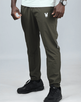 Person wearing green jogger pants with a logo on a gray background