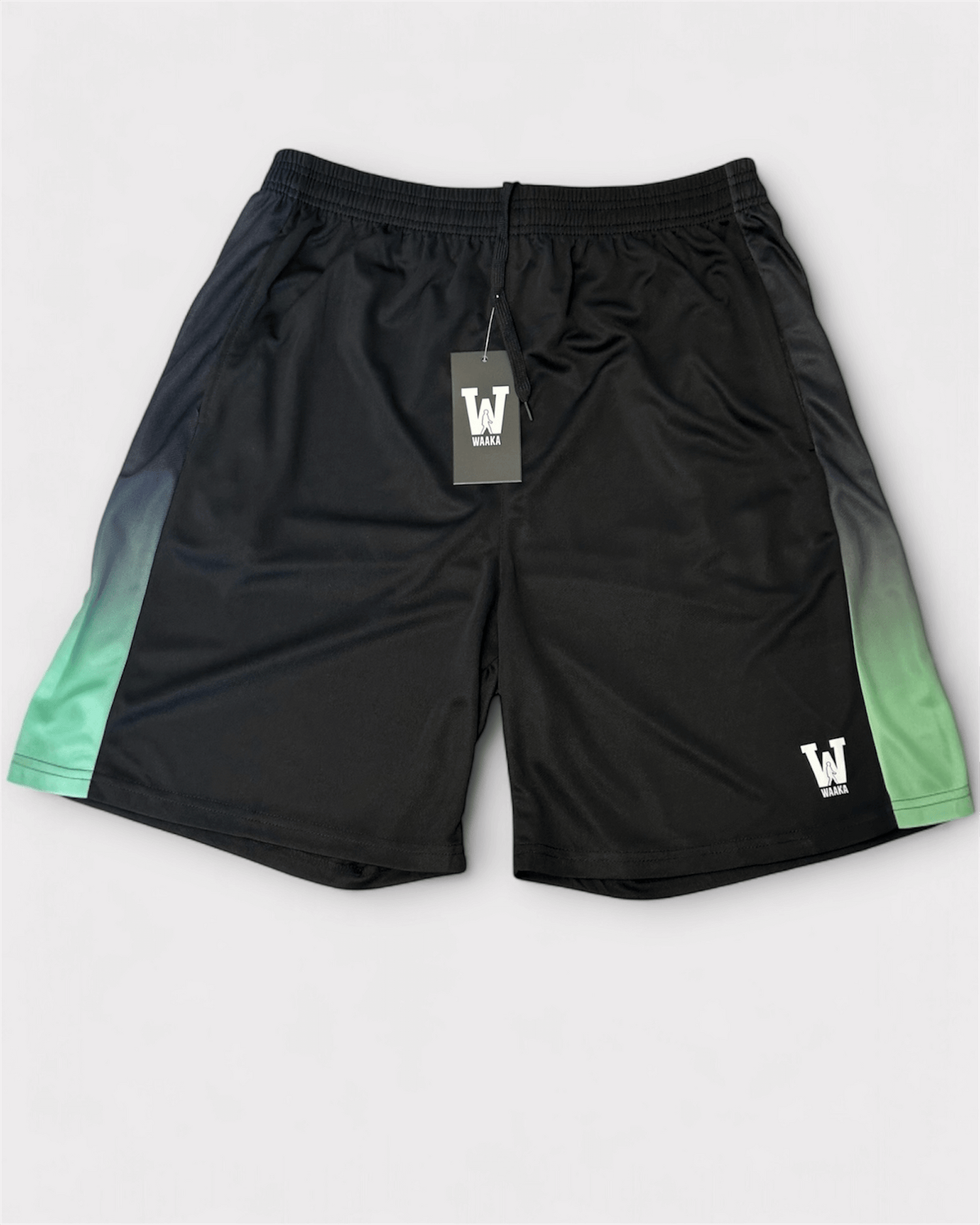 Black and green shorts with waaka brand tag on a white background