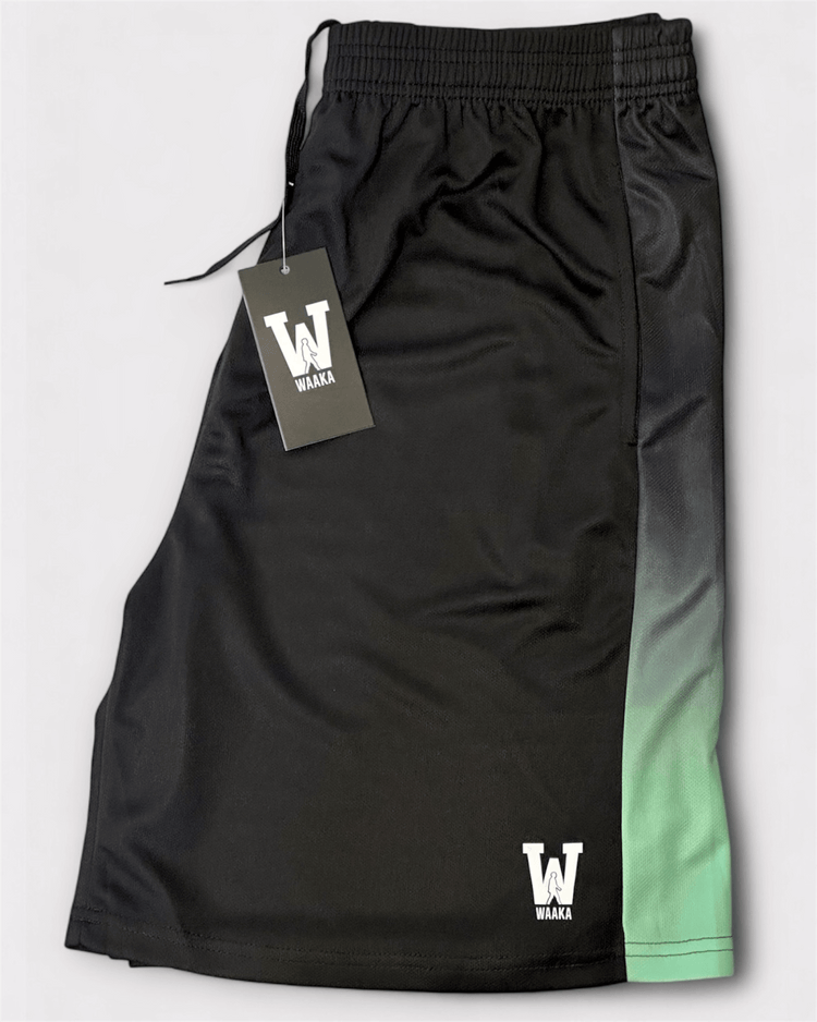 Black shorts with gradient design and Waaka tag on a light gray background