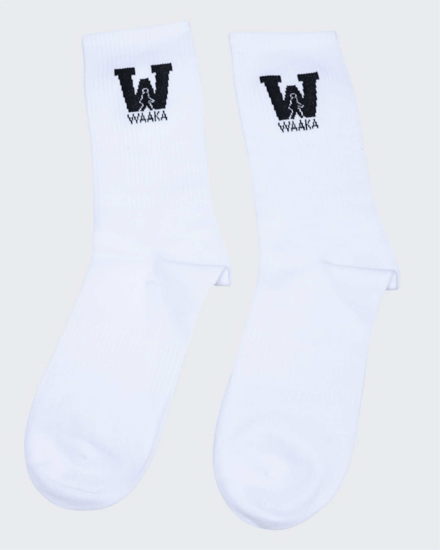 Two white socks with a black waaka logo on a light beige background