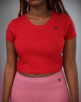 woman wearing a red crop top and pink leggings with waaka logo on a grey background