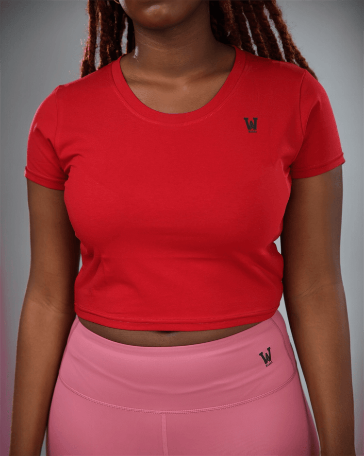 woman wearing a red crop top and pink leggings with waaka logo on a grey background
