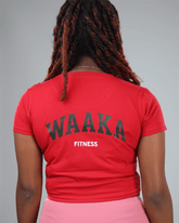 woman wearing a red crop top and pink leggings with waaka logo on a grey background back view