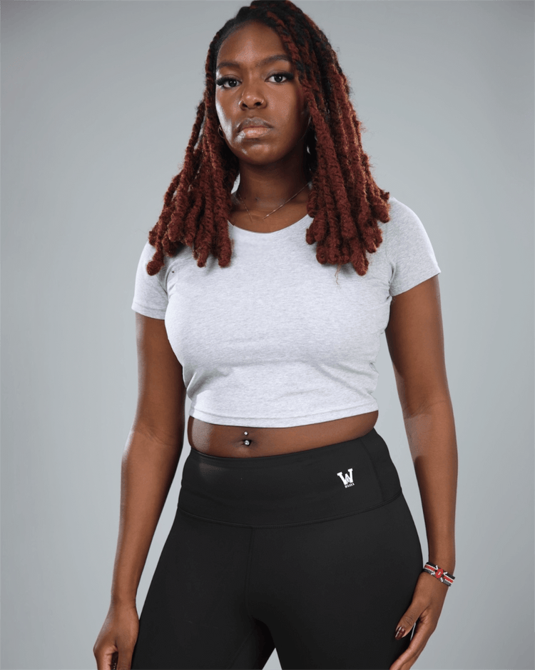 Person wearing a grey crop top and black leggings with waaka logo on a gray background