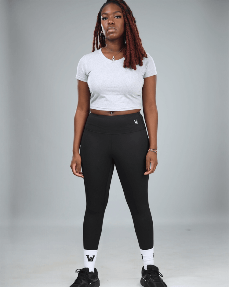 Person wearing a grey crop top t-shirt with waaka logo on a grey background full studio shot