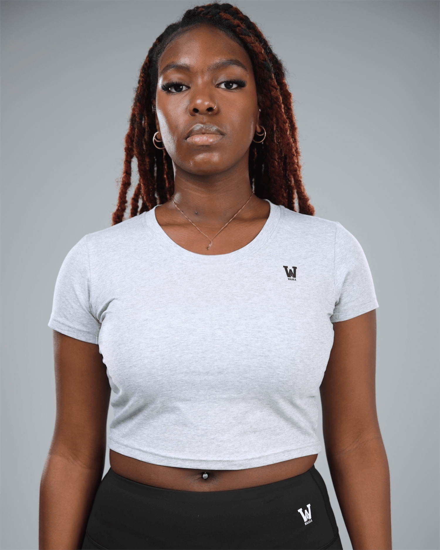 Person wearing a grey crop top t-shirt with waaka logo on a grey background