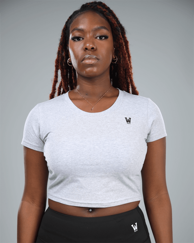 Person wearing a grey crop top t-shirt with waaka logo on a grey background