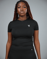 Woman wearing a black short sleeve  t-shirt with a logo on a grey background front view