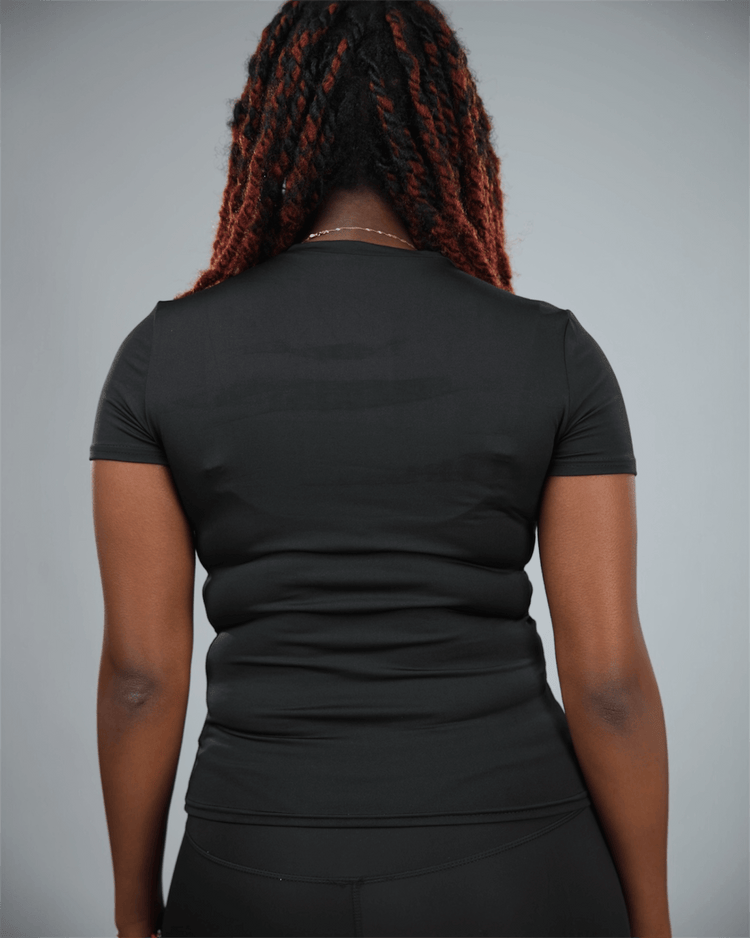 Woman wearing a black short sleeve  t-shirt with waaka logo on a grey background back view