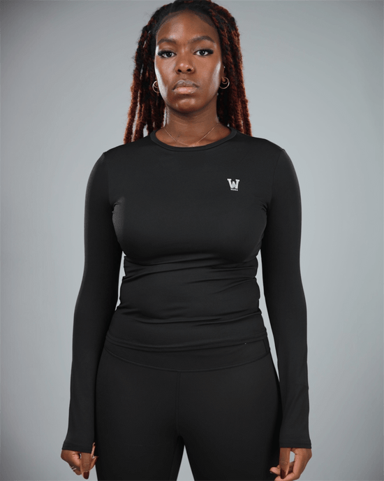 Person wearing a black long-sleeve athletic top with waaka logo on a gray background