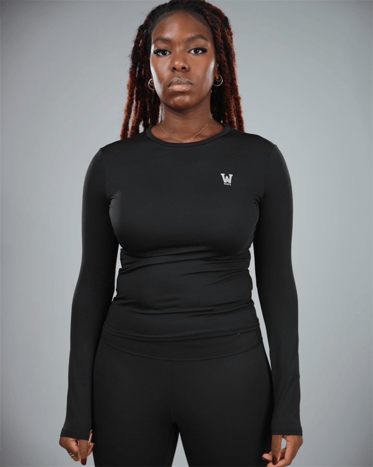 Person wearing a black long-sleeve athletic top with waaka logo on a gray background