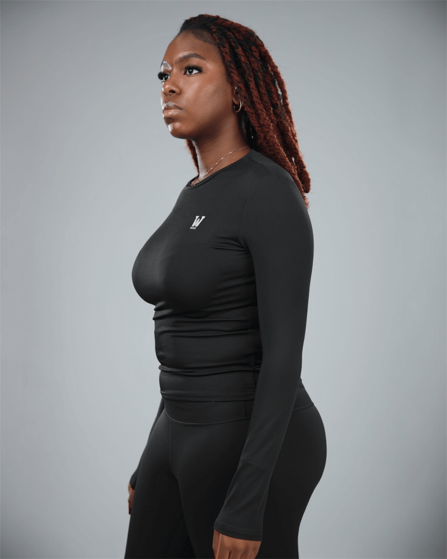 Woman wearing a black long-sleeve athletic top and leggings on a gray background