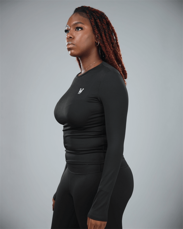 Woman wearing a black long-sleeve athletic top and leggings on a gray background