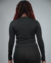 Person wearing a black long-sleeve top against a gray background back view