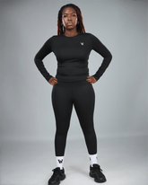 Person wearing a black athletic outfit with a logo on a gray background