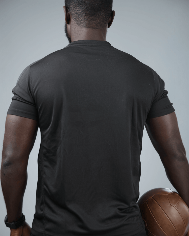 Man wearing the black grey eco training t-shirt holding a medicine ball against a gray background back view