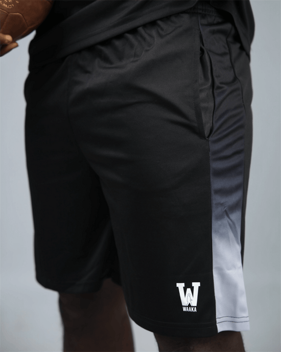 Black eco training athletic shorts with a white waaka logo on a grey background