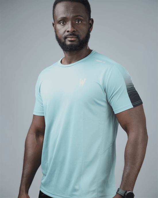 Man wearing a light blue eco training athletic shirt with waaka logo on a grey background