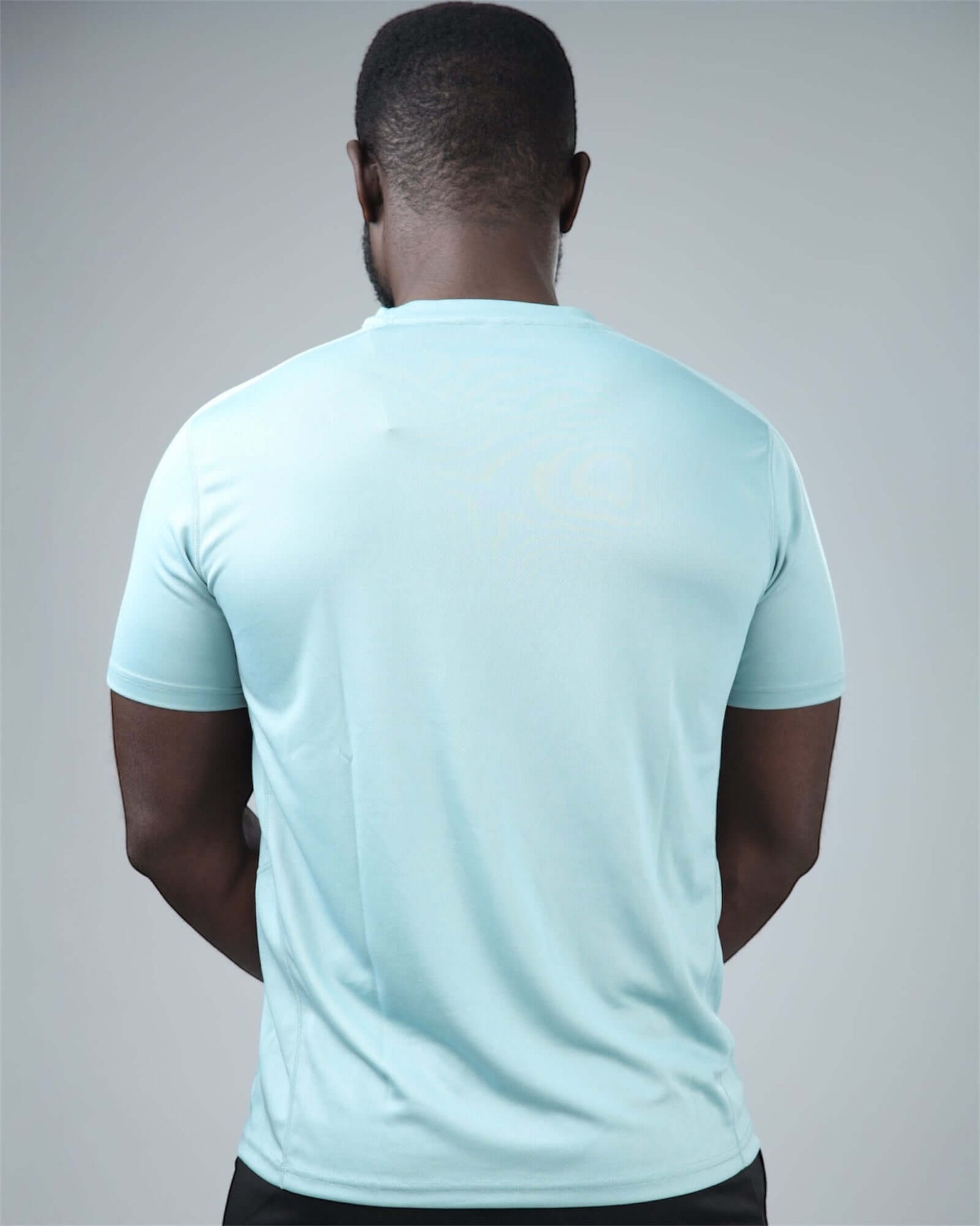 Person wearing a light blue t-shirt on a gray background back view