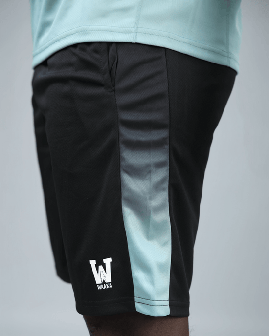 Black eco training shorts with a light blue stripe featuring waaka logo on a grey background