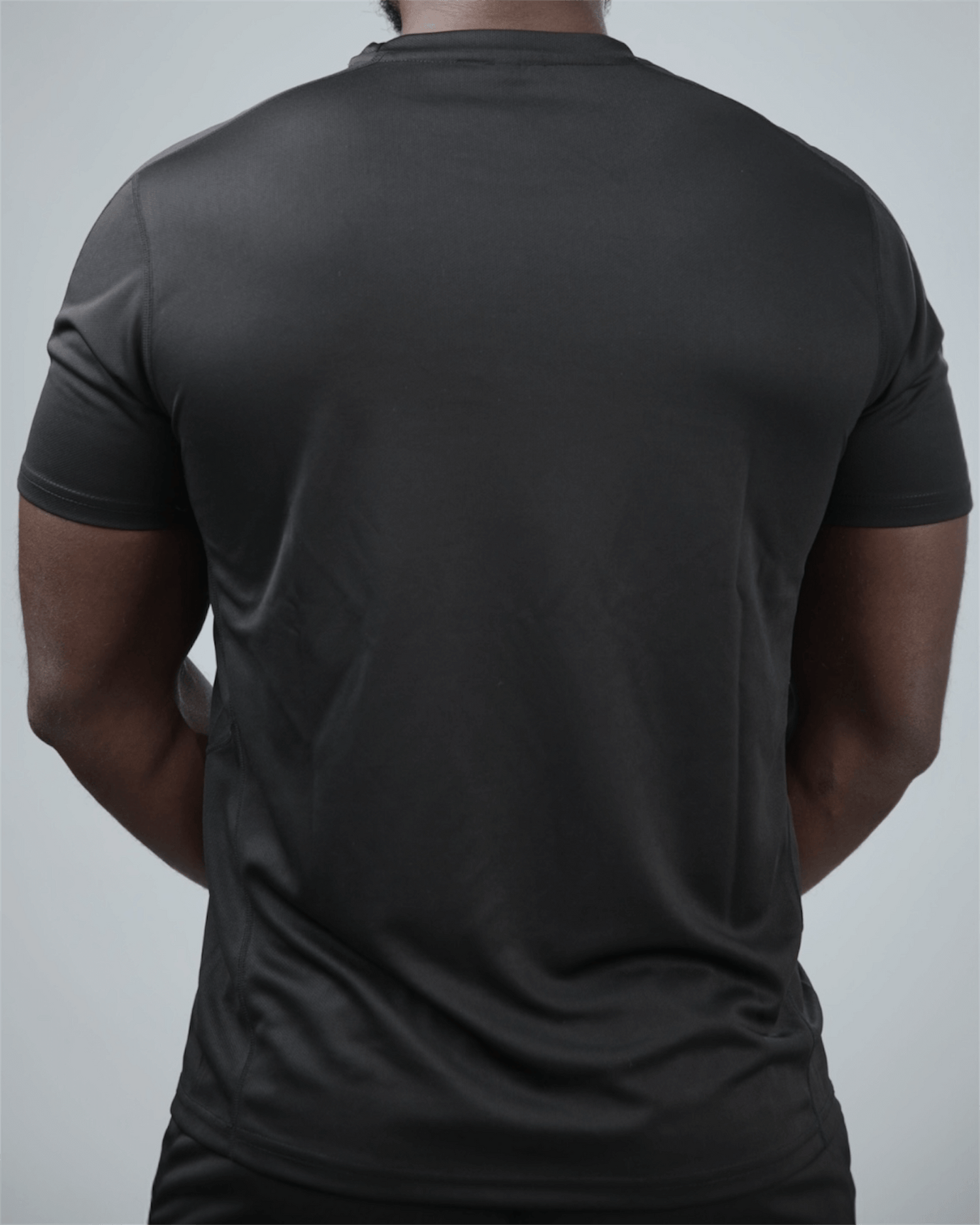 Person wearing a plain black t-shirt on a light gray background