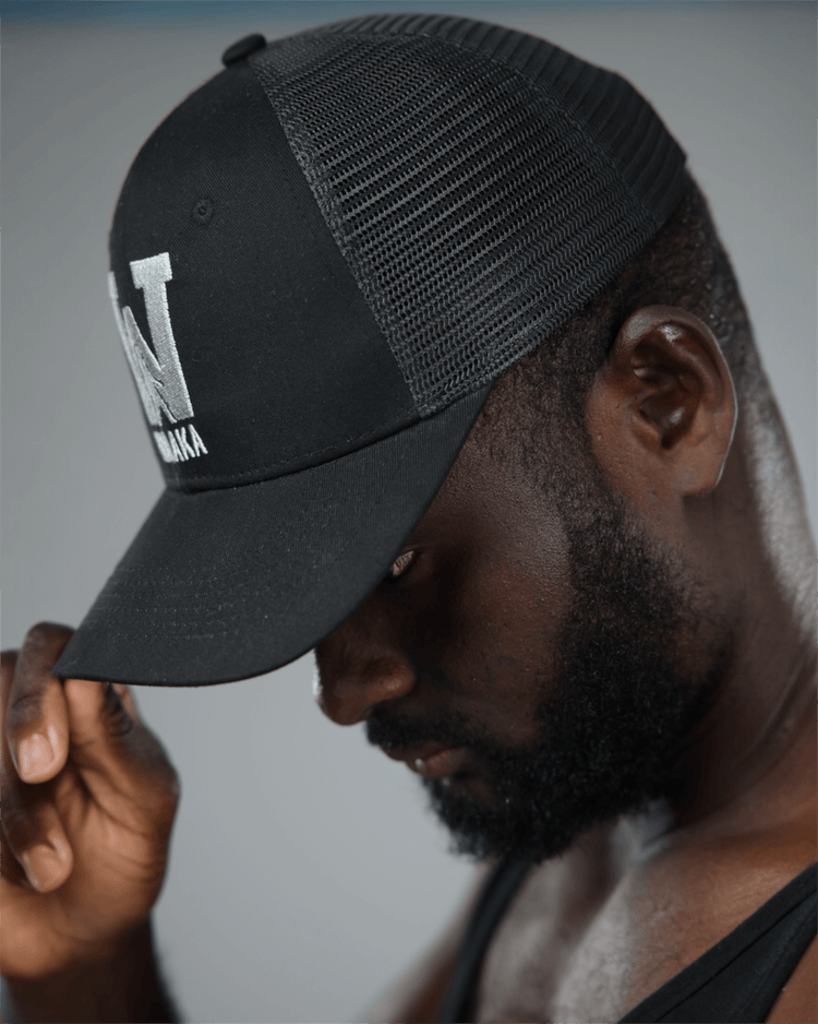 Man wearing a black cap with waaka logo, looking downwards.