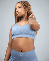 Woman wearing a blue sports bra and leggings against a gray background