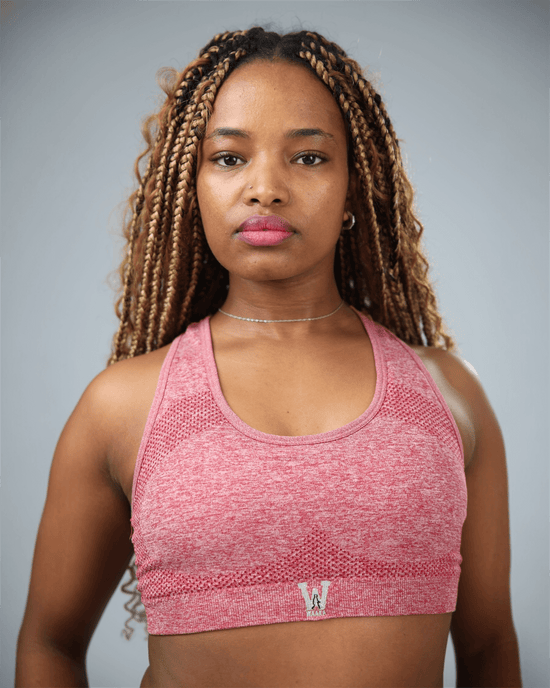 Red sports bra with waaka logo worn by a woman on a grey background