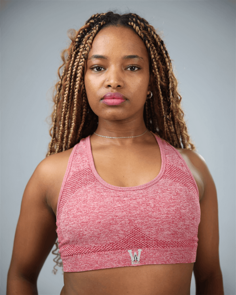 Red sports bra with waaka logo worn by a woman on a grey background