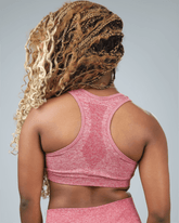 Person wearing a red sports bra and leggings with a gray background back view