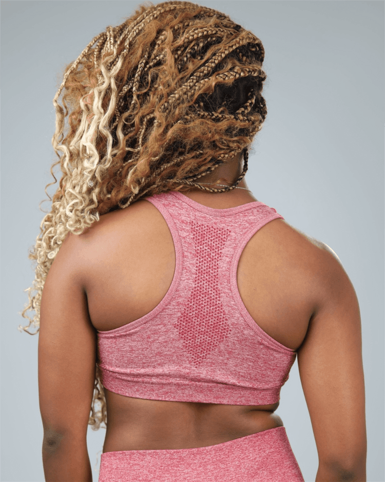 Person wearing a red sports bra and leggings with a gray background back view