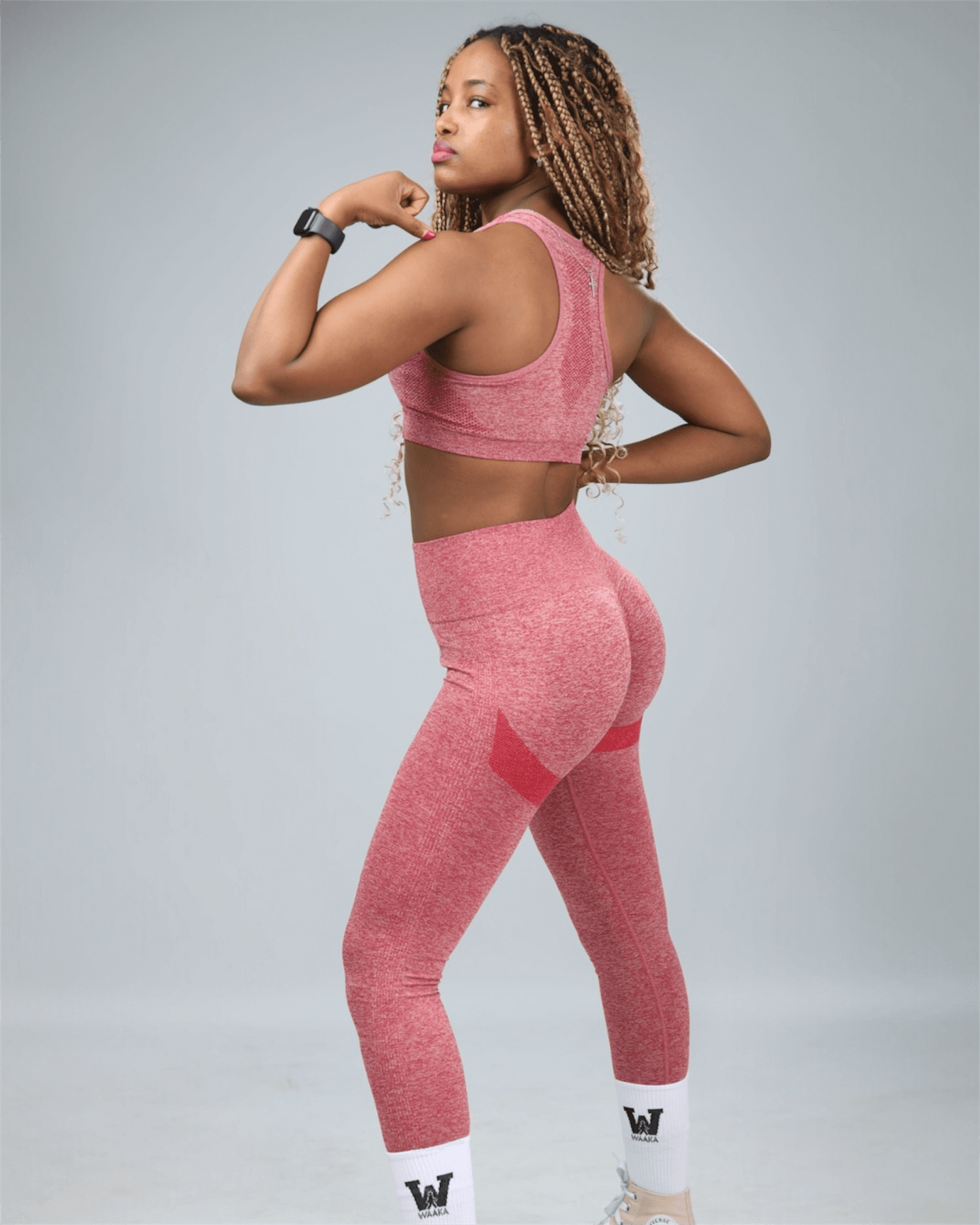 Person wearing a red athletic outfit on a gray background flexing muscle