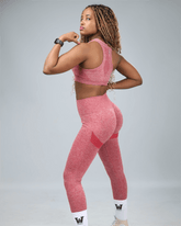 Person wearing a red athletic outfit on a gray background flexing muscle