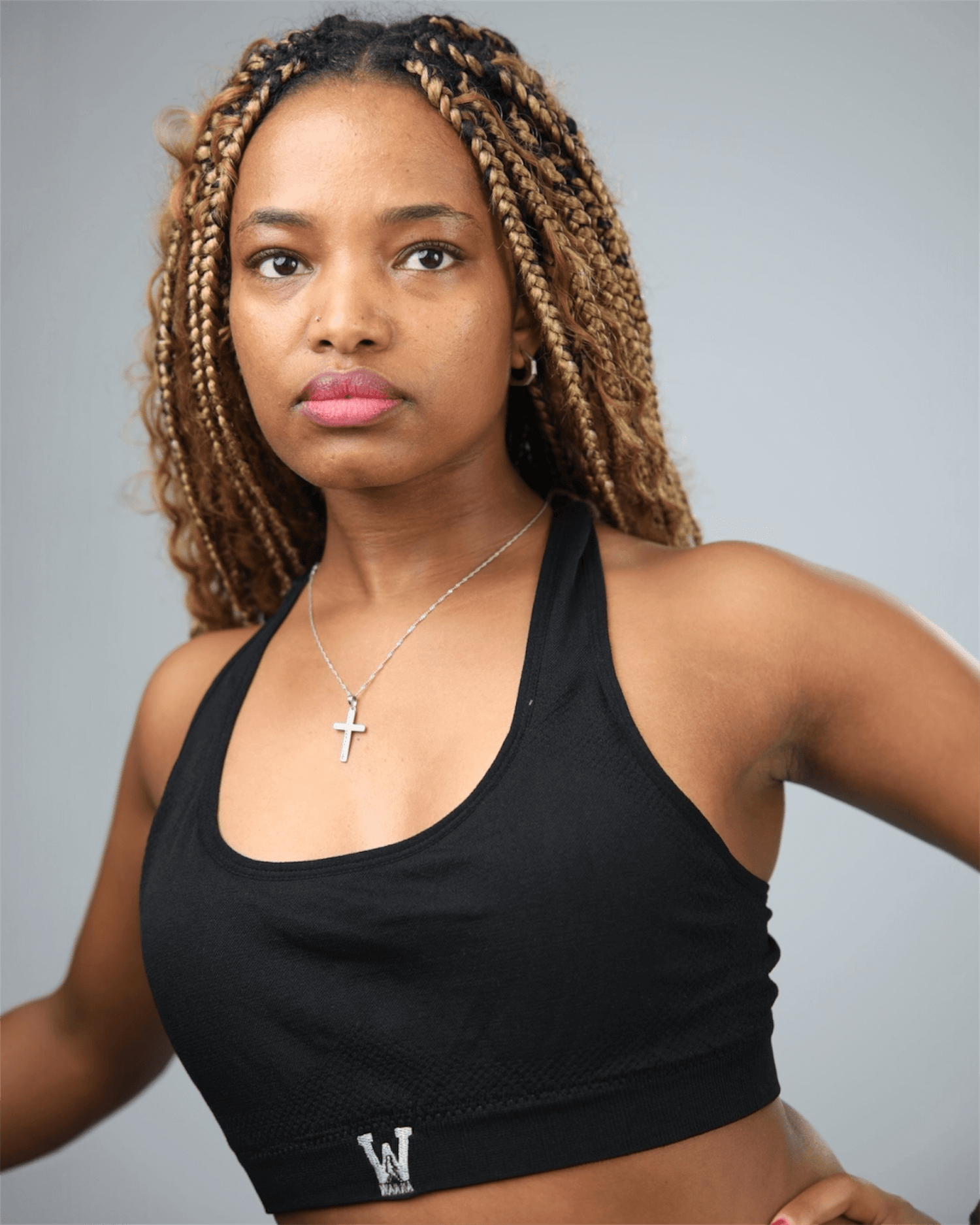 Woman wearing a black sports bra with waaka  logo on a grey background