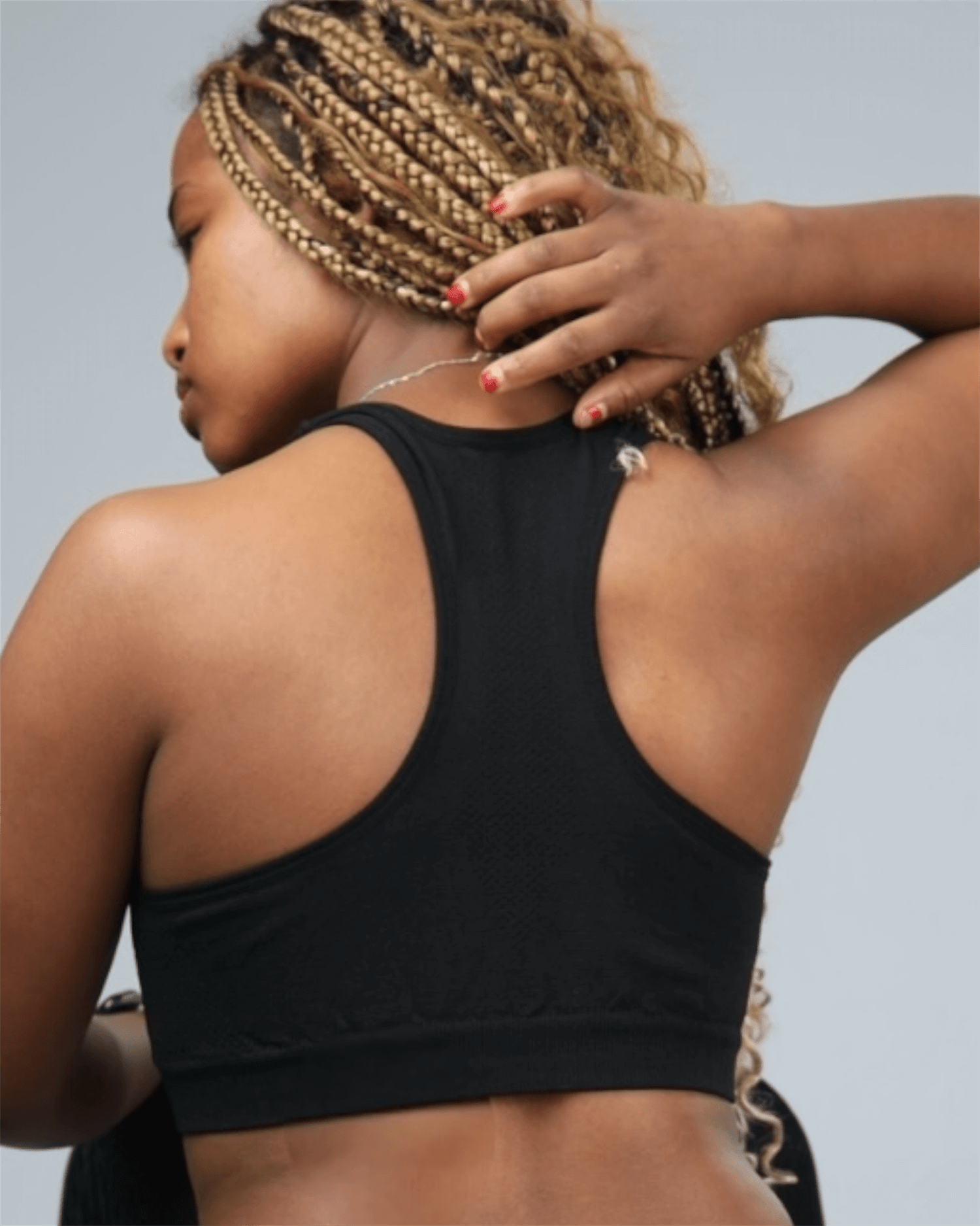 Person wearing a black sports bra with a neutral background baxk view