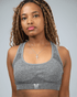 Woman wearing a grey sports bra with waaka logo on a plain background
