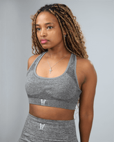 Woman wearing a gray sports bra and leggings against a plain background