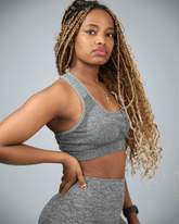 Woman wearing a gray athletic outfit against a plain background side view