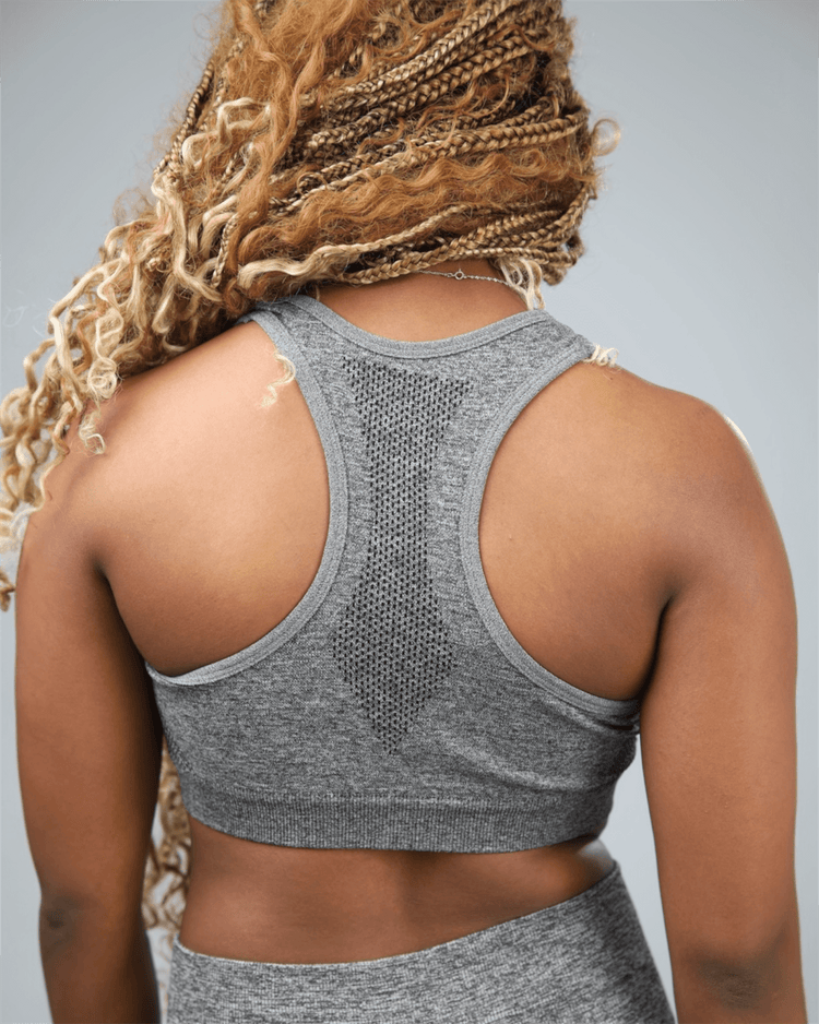 Person wearing a gray sports bra and leggings on a plain background
