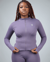 Woman wearing a purple athletic outfit with a logo on a gray background
