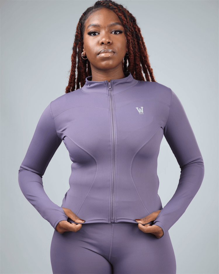 Woman wearing a purple athletic outfit with a logo on a gray background