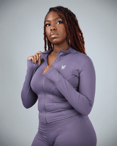 Woman wearing a purple athletic outfit with waaka logo on a gray background