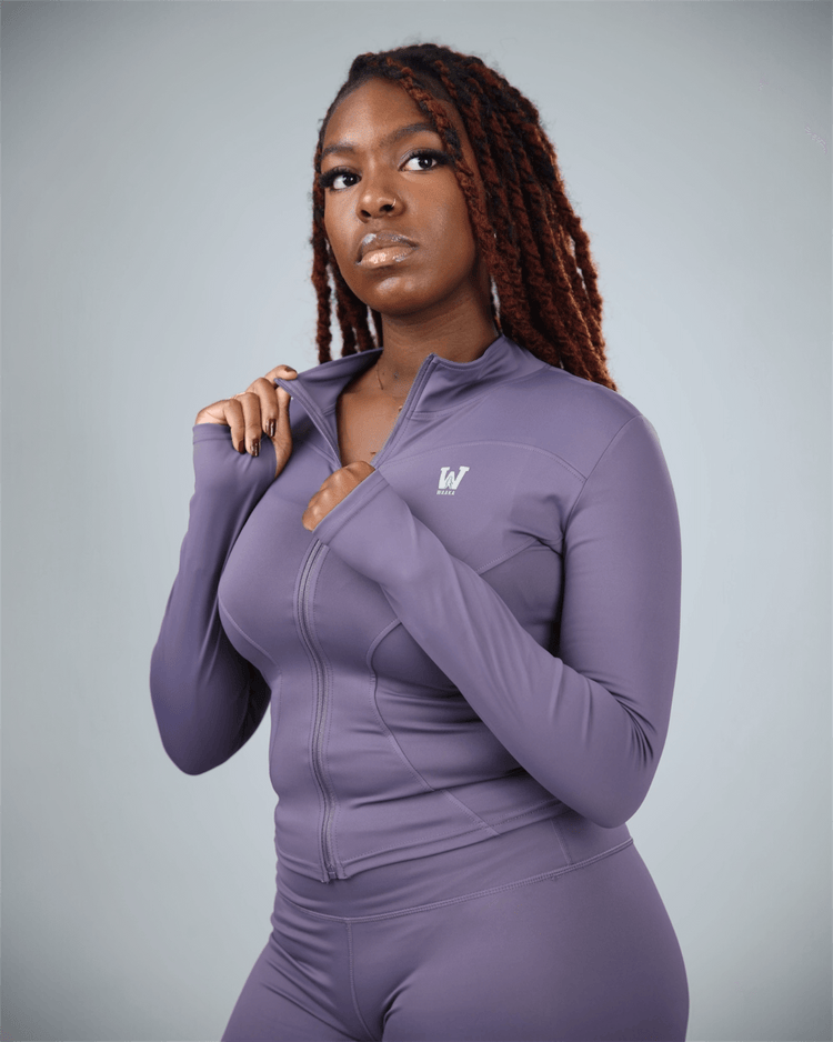 Woman wearing a purple athletic outfit with waaka logo on a gray background