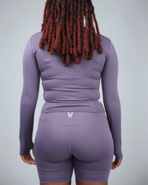 Person wearing a purple athletic outfit with waaka logo on a light gray background