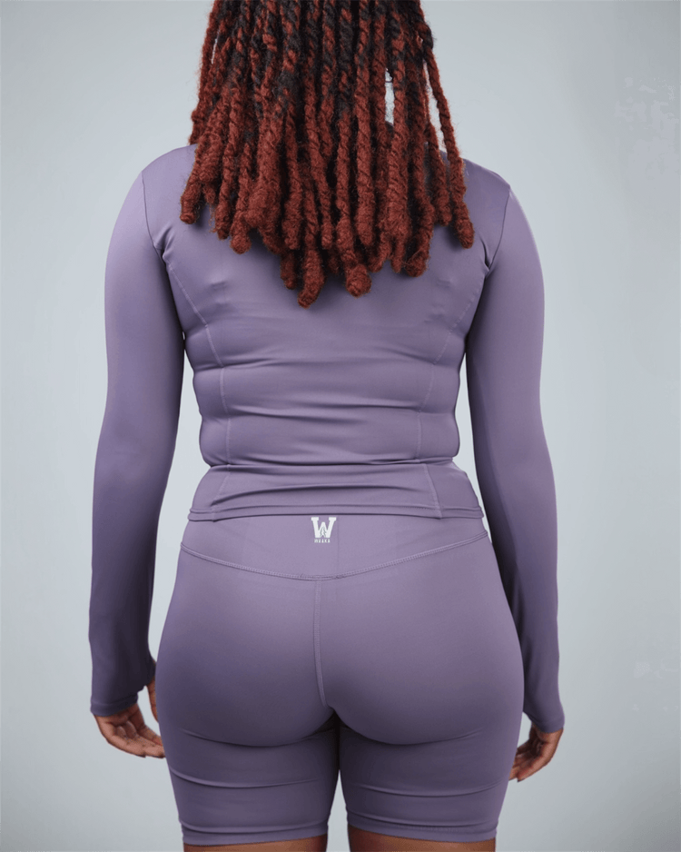 Person wearing a purple athletic outfit with waaka logo on a light gray background