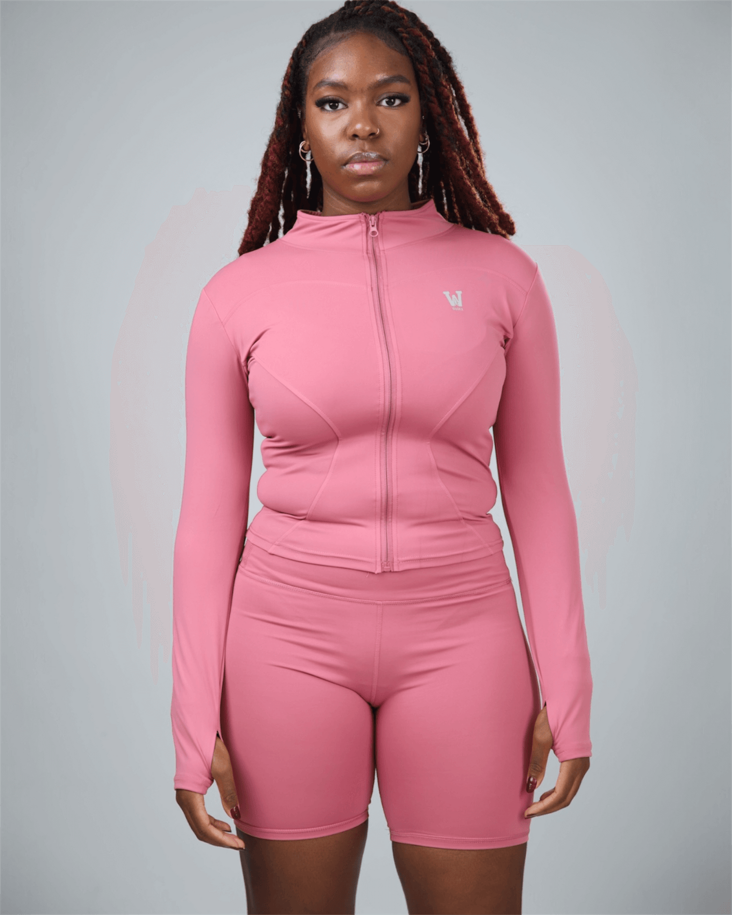 Person wearing a pink athletic outfit with a logo on a gray background