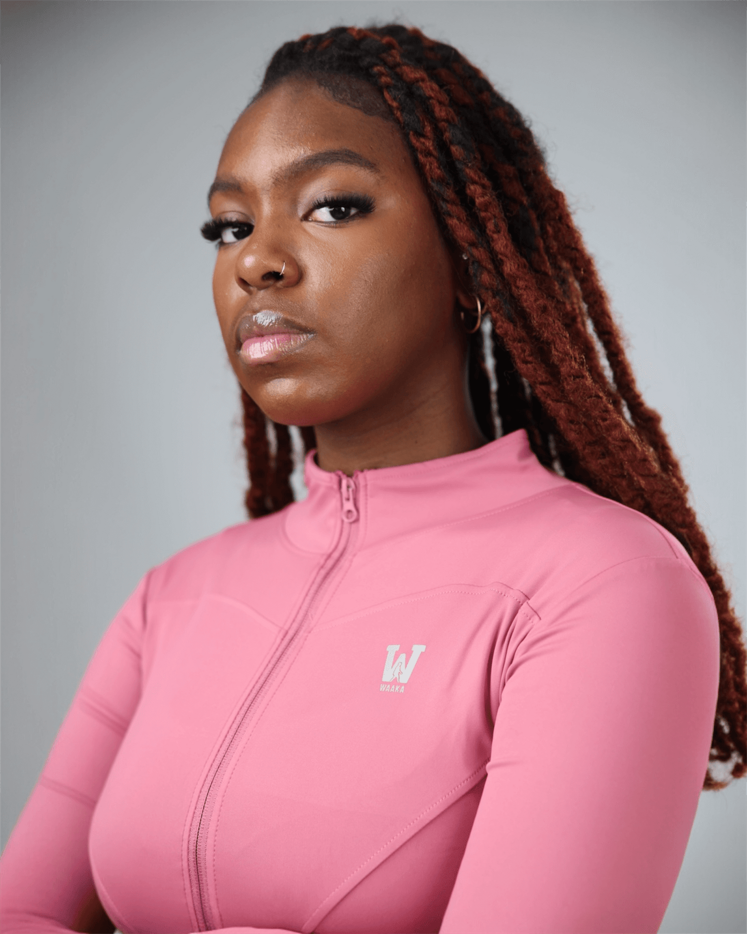 Woman wearing a pink long-sleeve top with a logo on a gray background