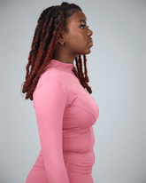 Woman wearing a pink long-sleeve top against a gray background
